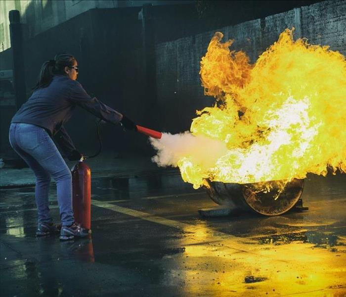 Girl demonstrating how to use a fire extingui0sher